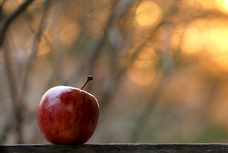 A close-up of a red apple resting on a wooden table, symbolizing love and spirituality.