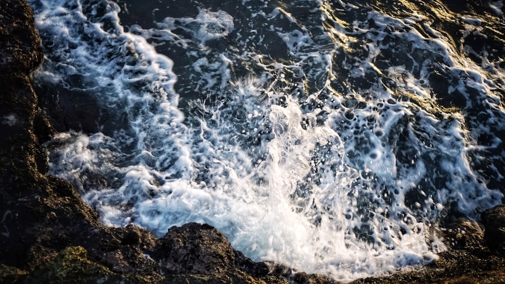 water waves hitting rocks during daytime