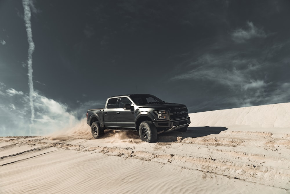 검은 시보레 승무원 택시 픽업 트럭 낮 동안 푸른 하늘 아래 갈색 모래 위에