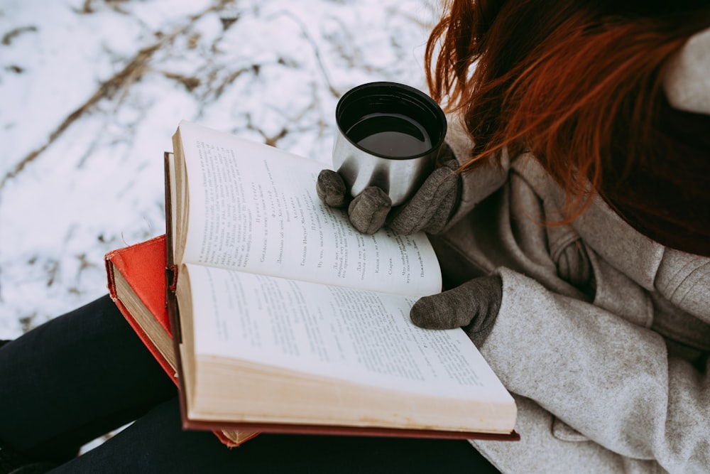 person in gray sweater reading book