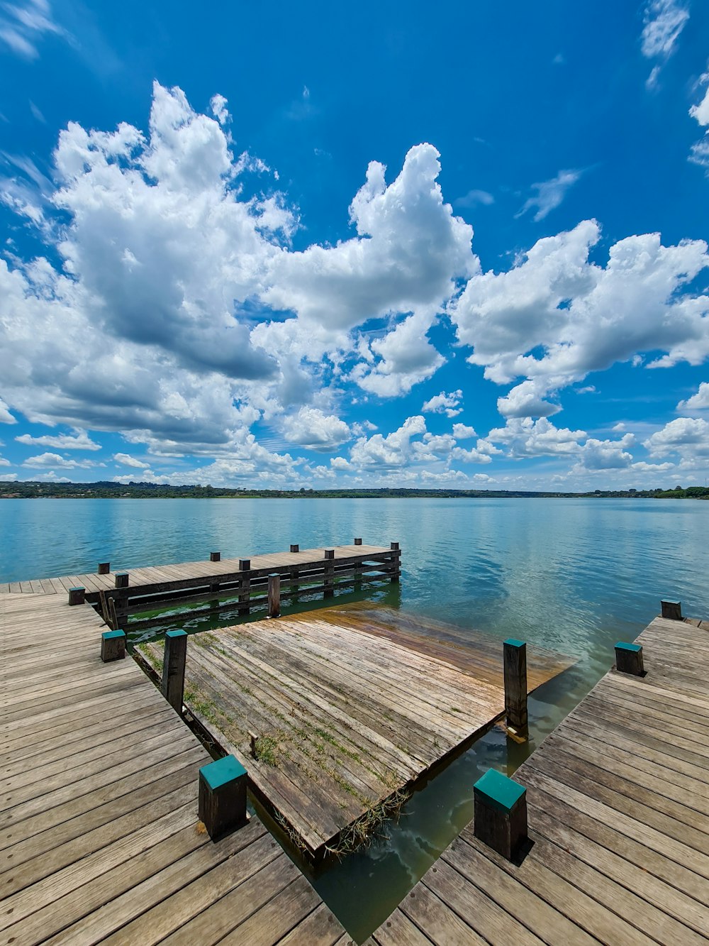 brown wooden dock on sea under blue and white cloudy sky during daytime