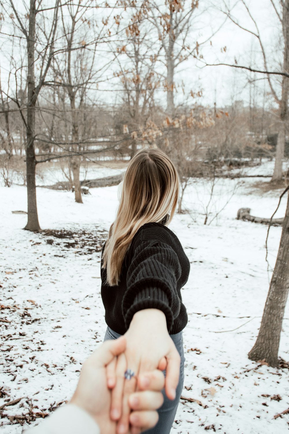 woman in black sweater standing on snow covered ground during daytime