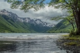 green and white mountains beside body of water under white clouds during daytime