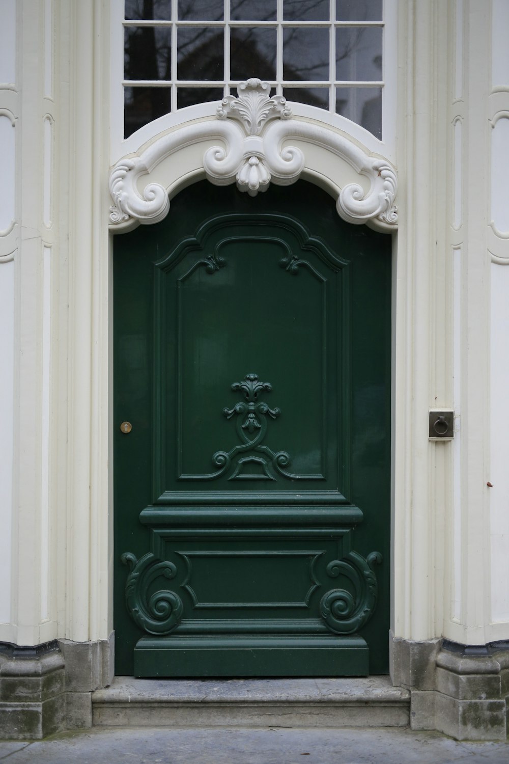 green wooden door with white concrete wall