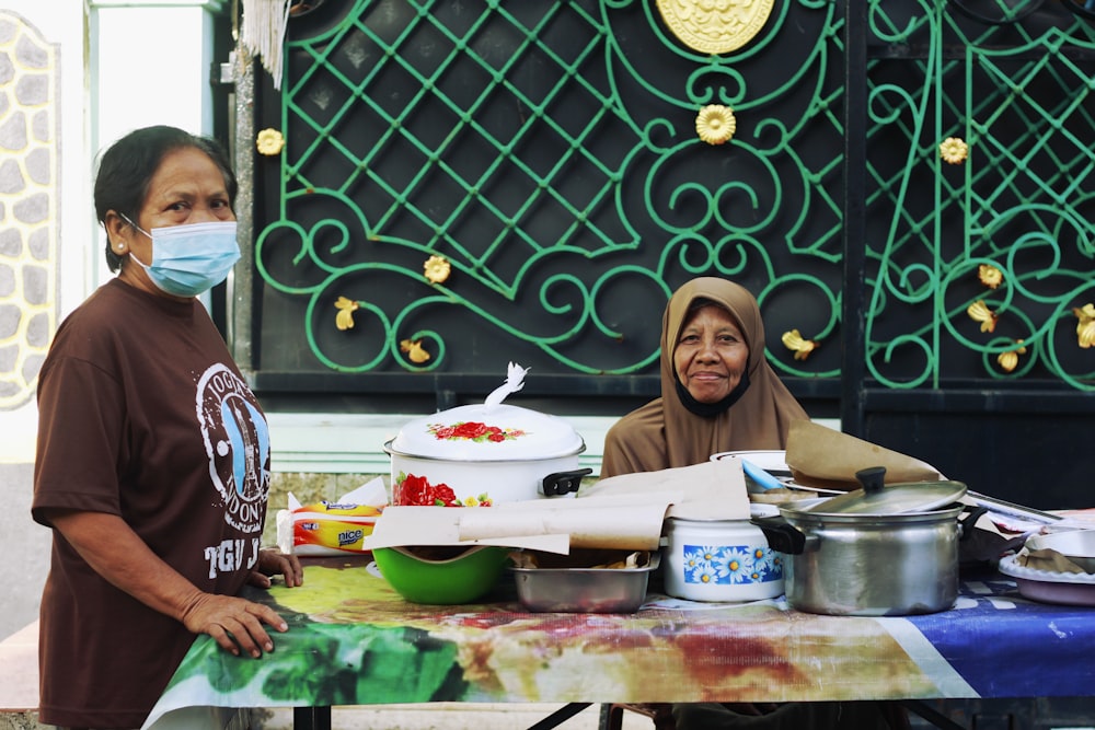 woman in black hijab sitting beside boy in red and white shirt