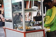 A street food cart with fresh ingredients and a friendly vendor serving customers.