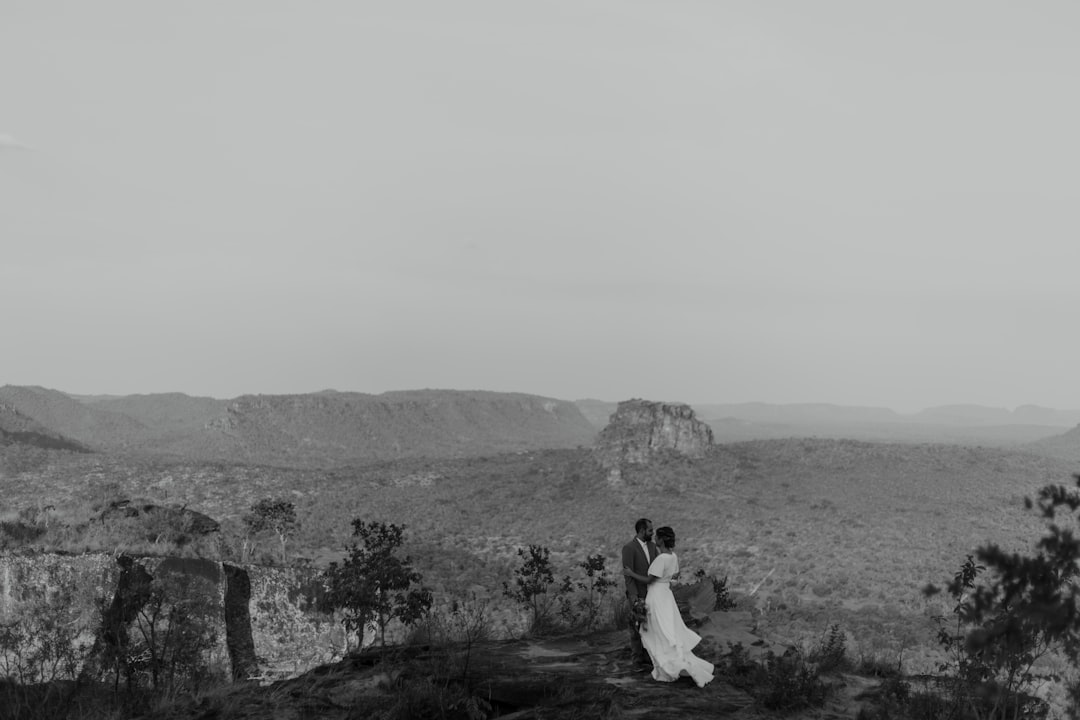 couple sitting on rock formation during daytime