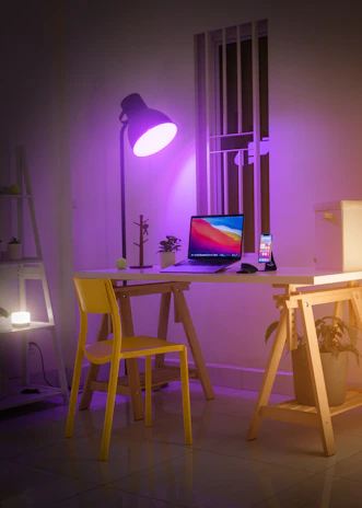 A creative workspace illuminated by purple and yellow lights, filled with sketches and tech gadgets.