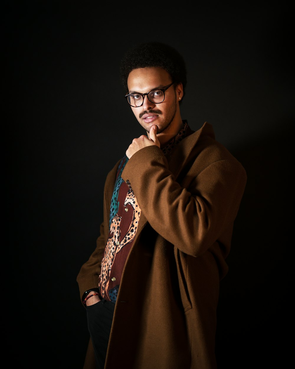 man in brown coat wearing black framed eyeglasses