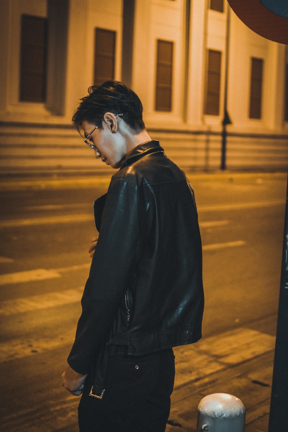 man in black coat standing on the sidewalk