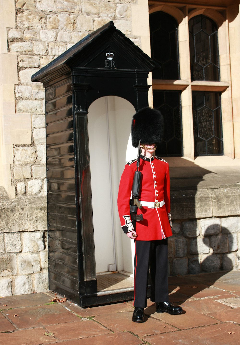 man in red coat standing near brown concrete building during daytime