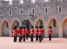 people in red and black uniform standing in front of brown concrete building during daytime