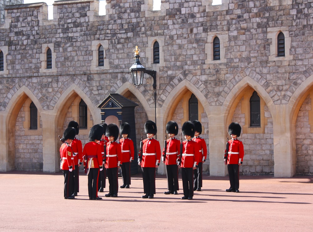 people in red and black uniform standing in front of brown concrete building during daytime