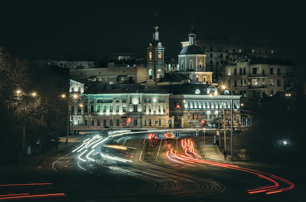 a city street at night with a large building in the background