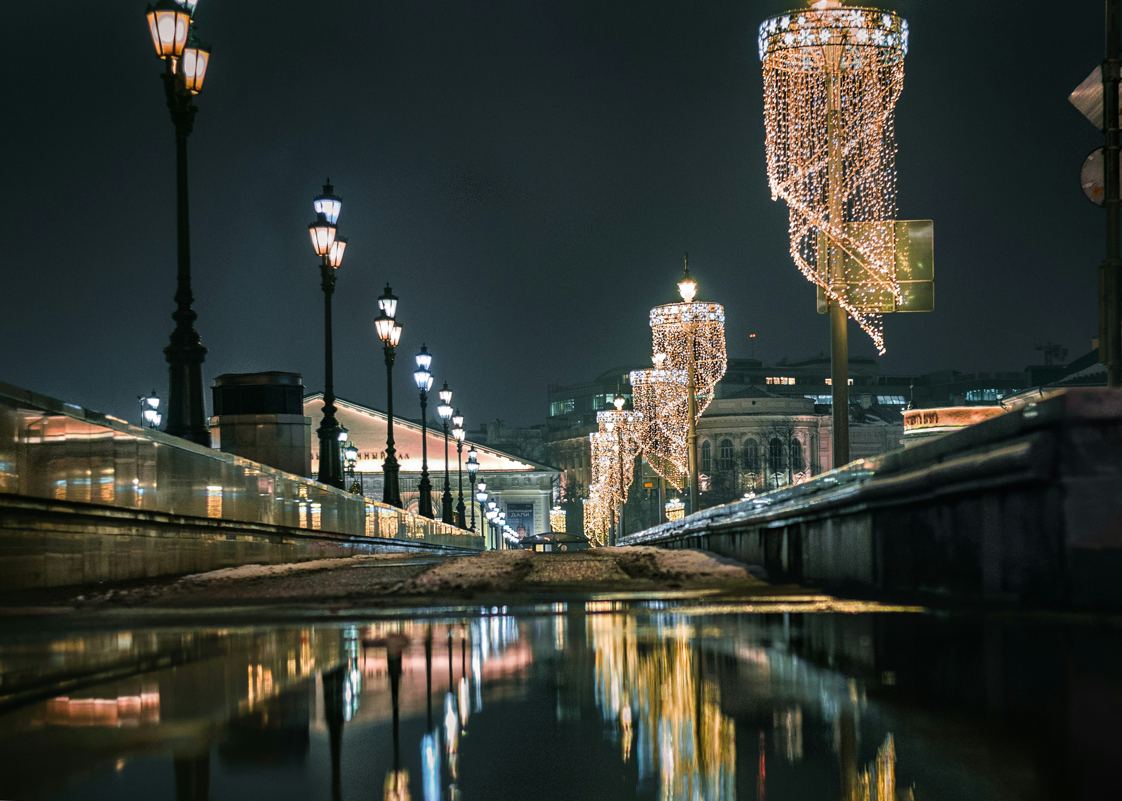 a city street filled with lots of lights next to a body of water