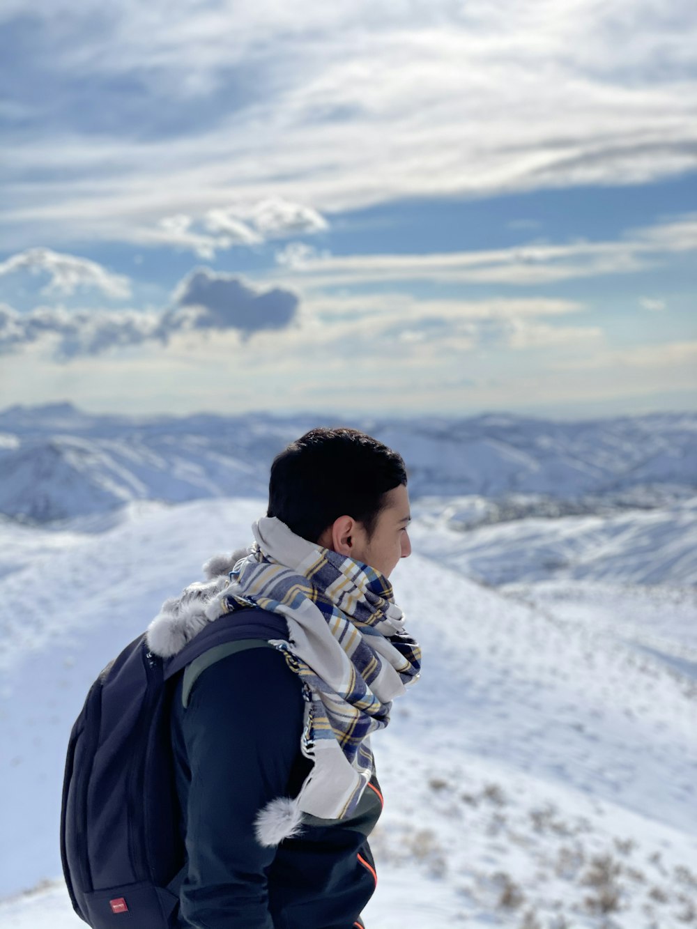 man in black jacket carrying backpack on snow covered mountain during daytime