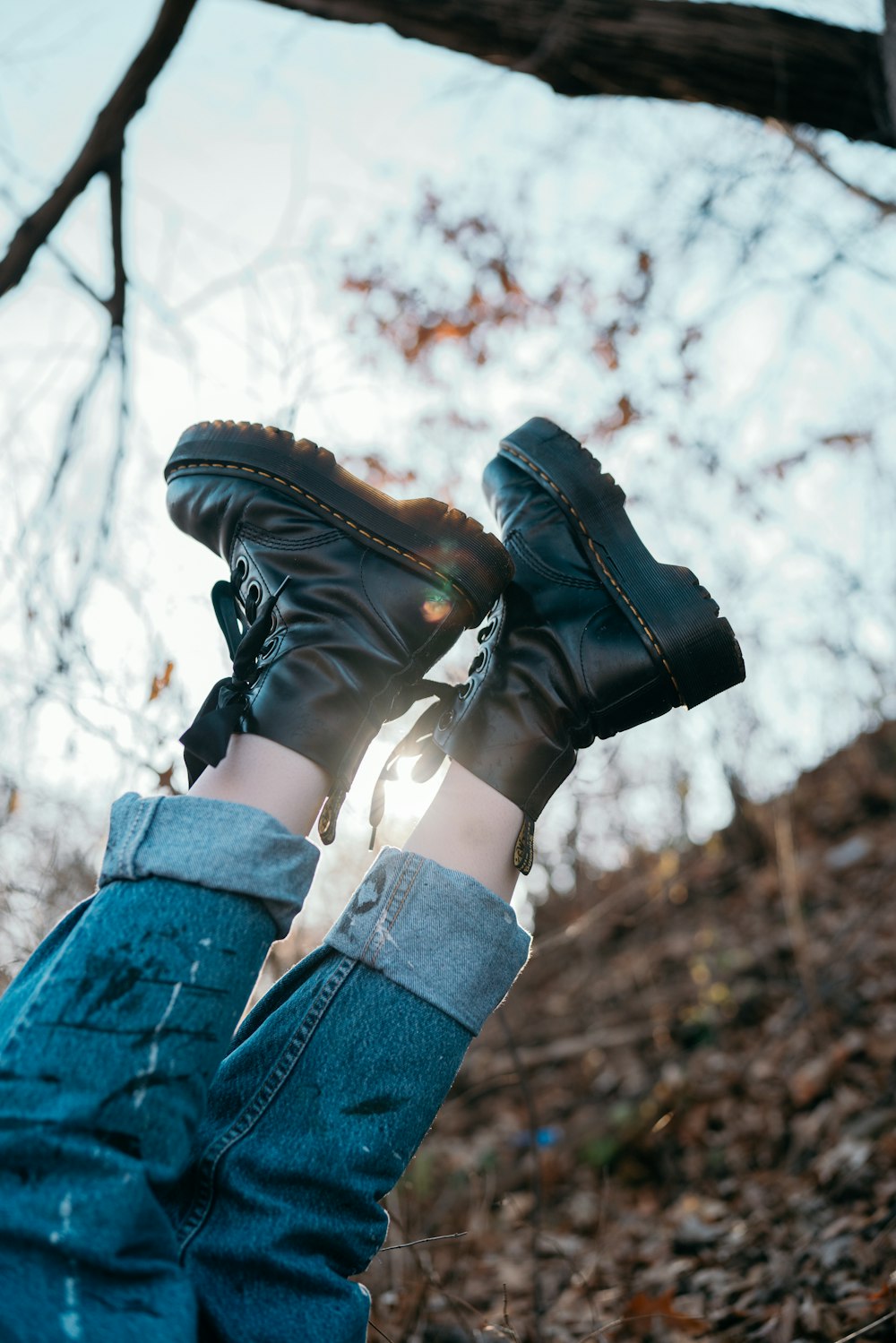 person in blue denim jeans and black leather boots