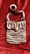A crocheted handbag featuring a striped pattern with alternating rows of brown, white, and small pink accents. The bag has a flap closure and a single strap, displayed against a textured, deep red fabric background.