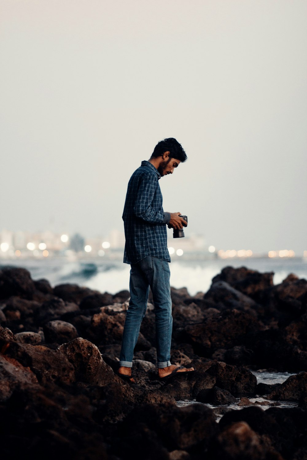 man in blue and white plaid dress shirt and blue denim jeans standing on rock near near near near near