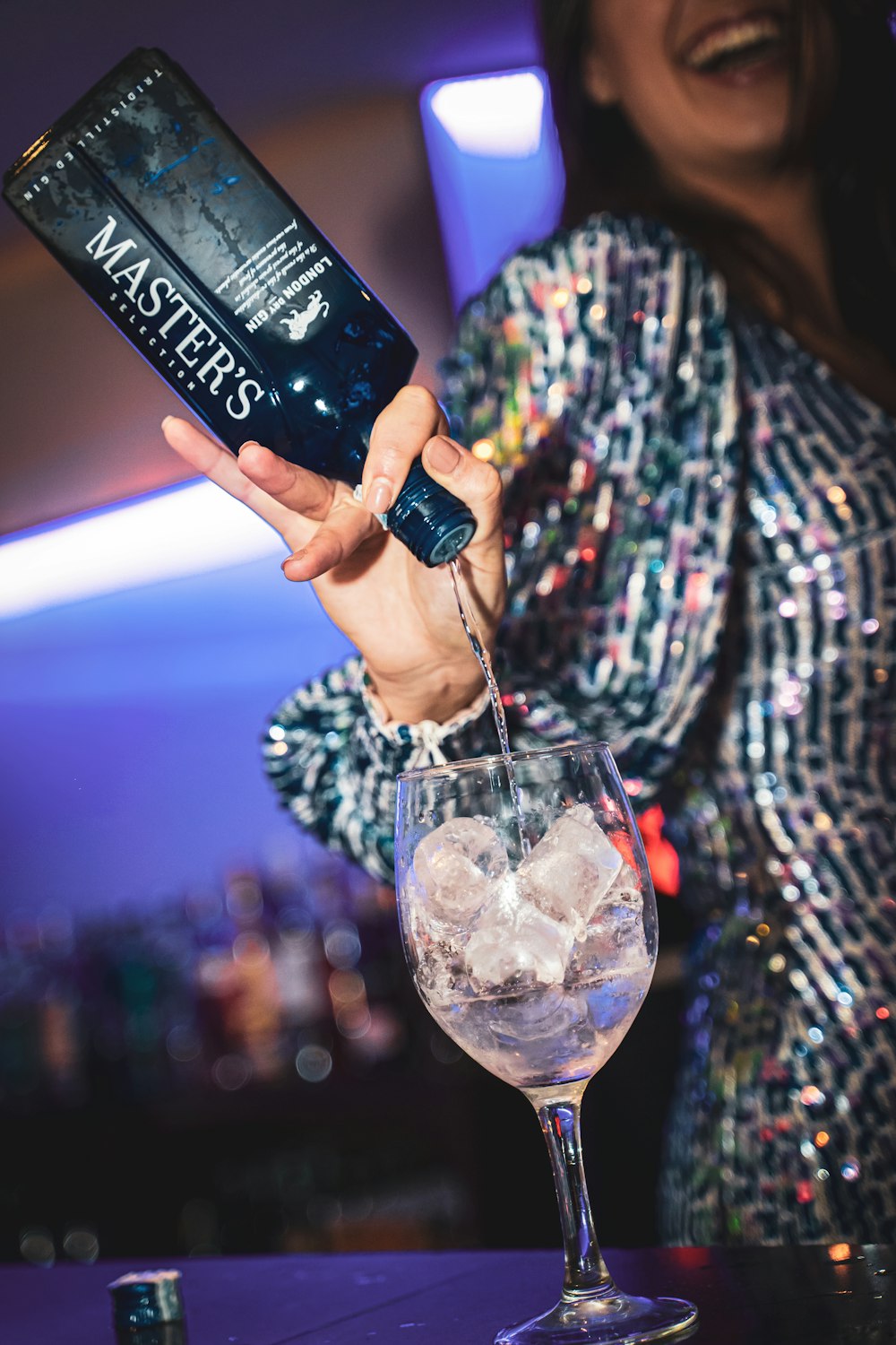 person holding black and white bottle pouring water on clear drinking glass