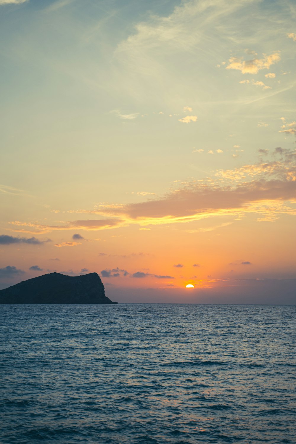 silhouette of mountain beside sea during sunset