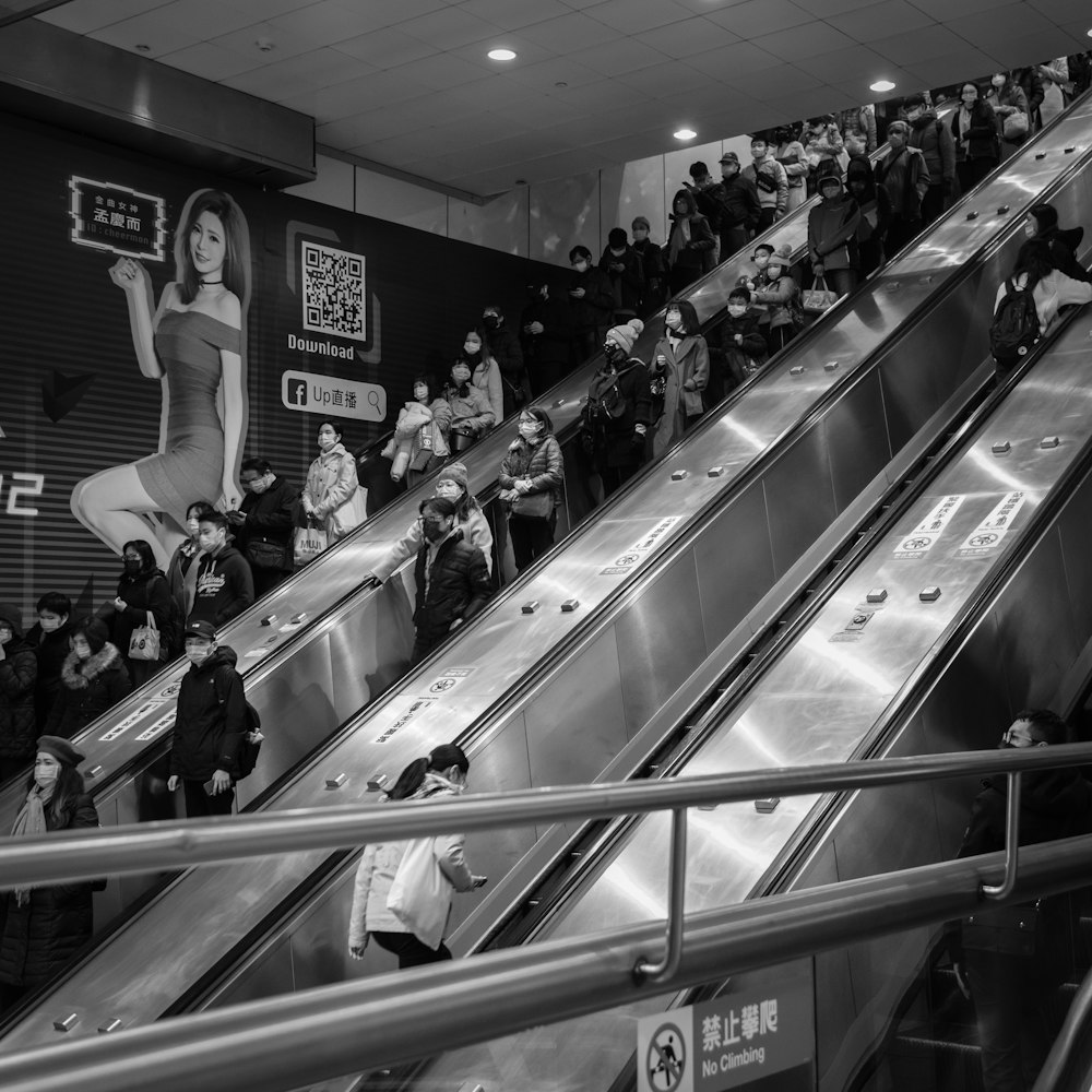 grayscale photo of people in a escalator