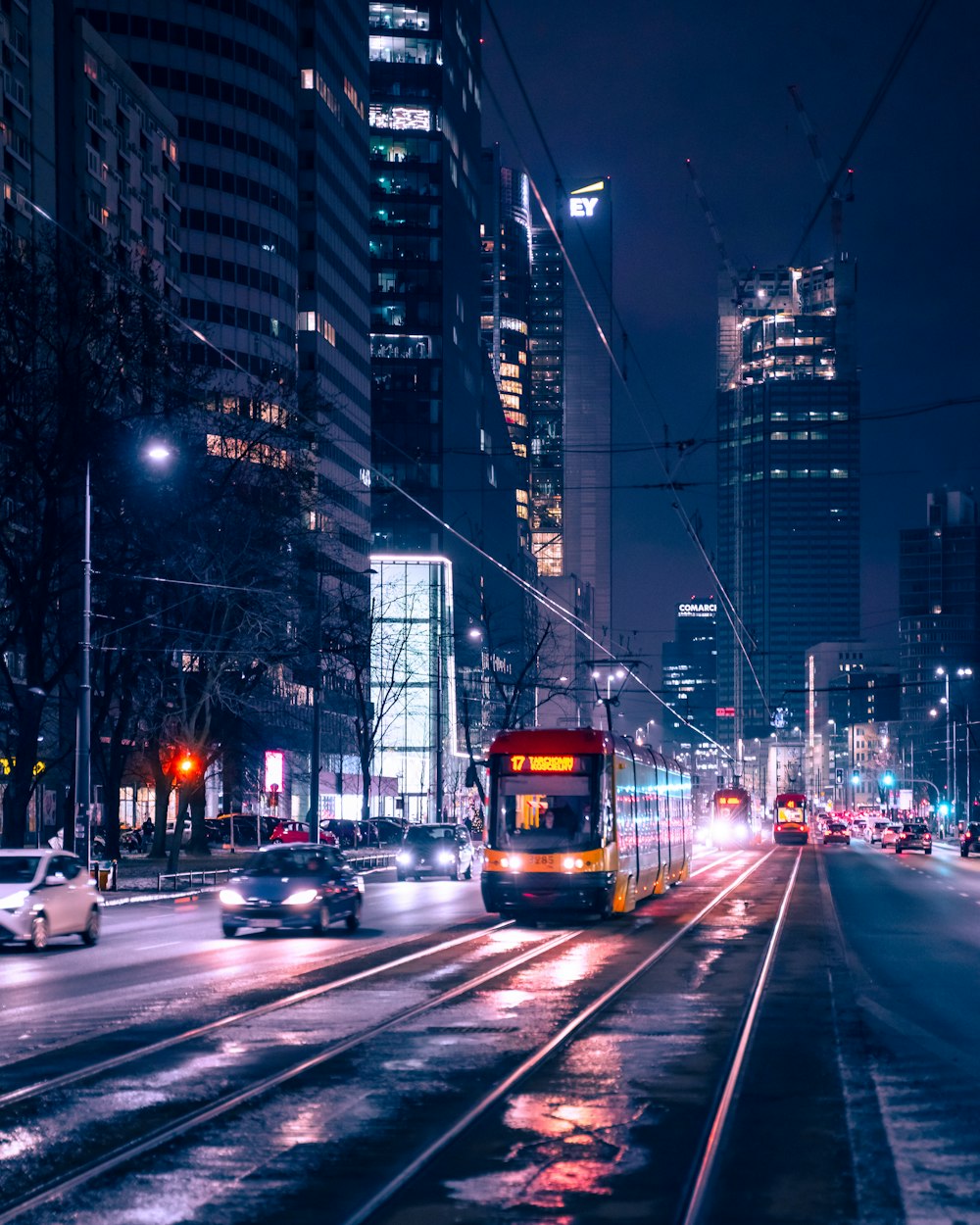 cars on road between high rise buildings during night time