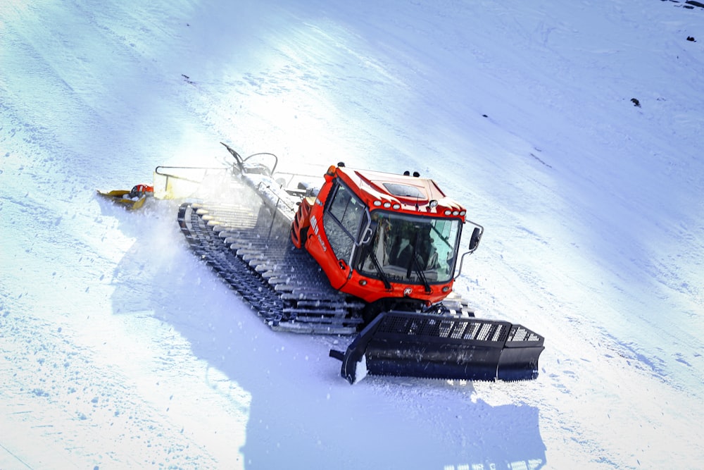 orange and black snow blower on snow covered ground during daytime