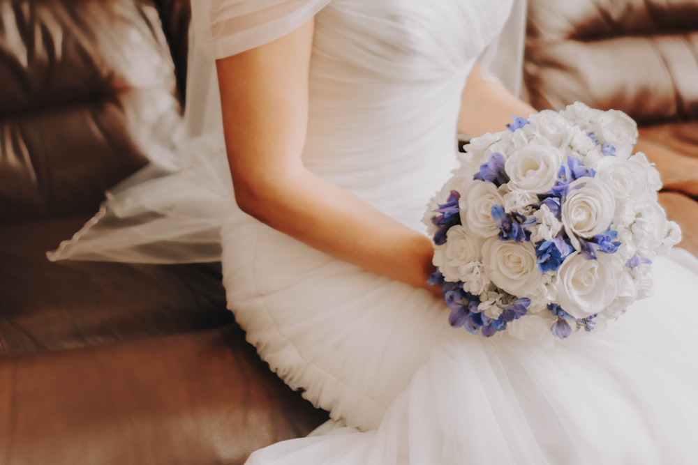 woman in white dress holding blue flower bouquet
