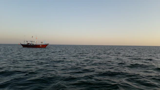 A calm sea with a fishing boat preparing for a trip at sunrise.