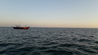 A vibrant fishing boat gliding over calm blue waters near Unawatuna at sunset.