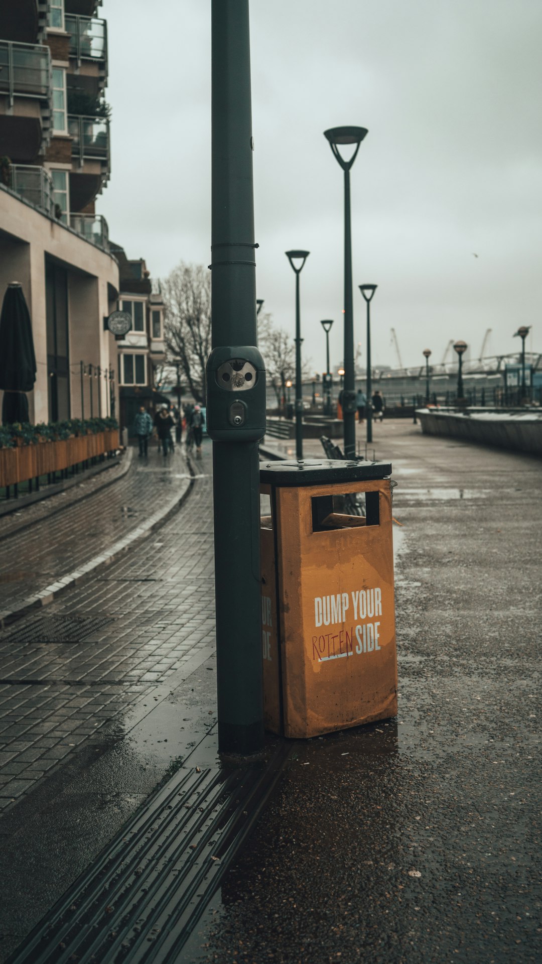 orange and black trash bin on sidewalk during daytime