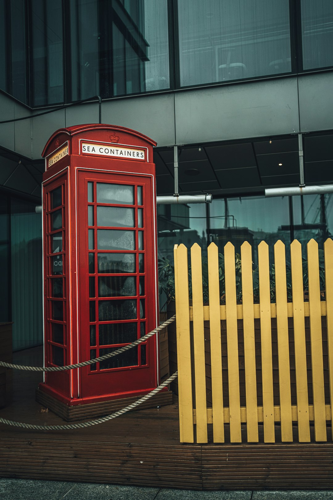 red telephone booth near yellow fence