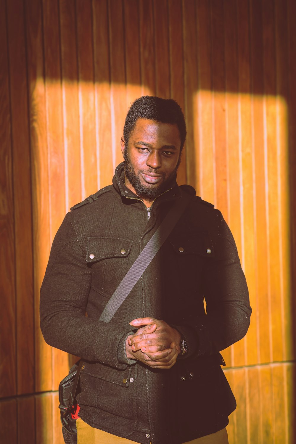 man in black jacket standing near brown curtain