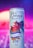 A can of blueberry-flavored energy drink featuring vibrant artwork of a rooster wearing a hat. The can design includes colorful illustrations with electric blue and red hues, surrounded by decorative elements like leaves and lightning bolts. The background is a gradient of purples and pinks with a soft, blurred effect.