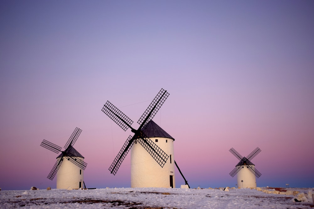 weiße und schwarze Windmühle auf weißem Sand während des Tages