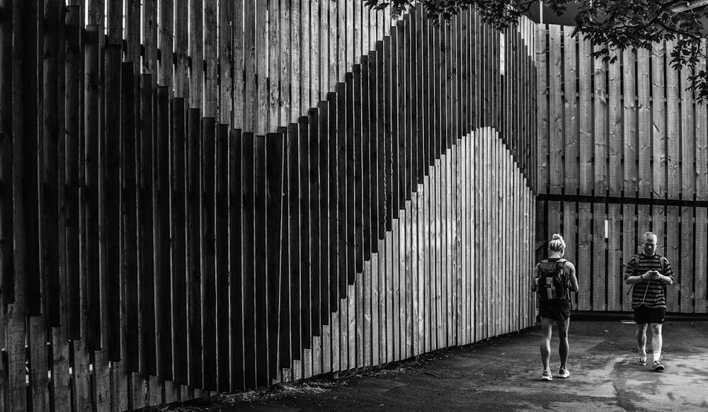 person walking on sidewalk near white and black wall