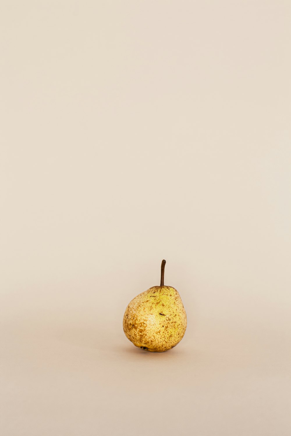 a single pear sitting on a white surface