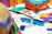 A close-up of a vibrant, hand-painted t-shirt laid out on a wooden table with paintbrushes nearby.