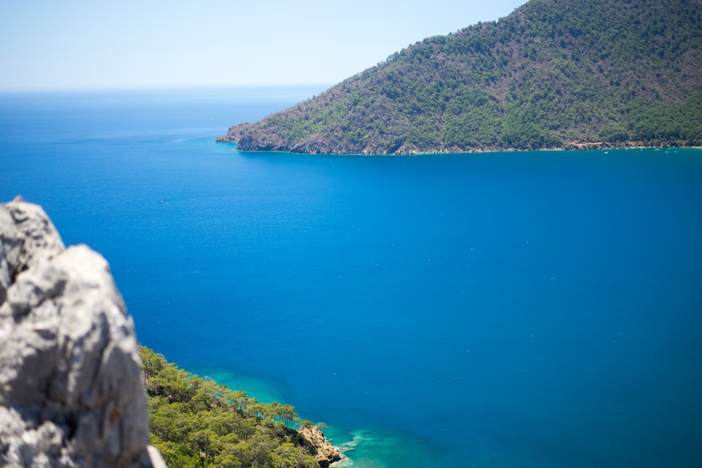 blue sea beside green mountain during daytime