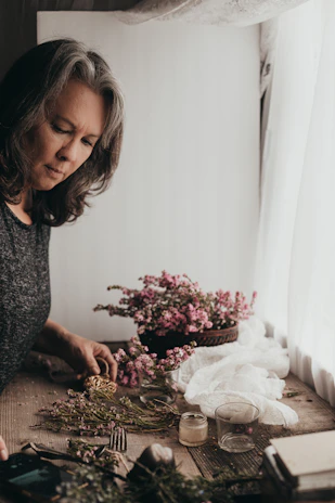 A cheerful customer arranging colorful silk flowers on a rustic wooden table.