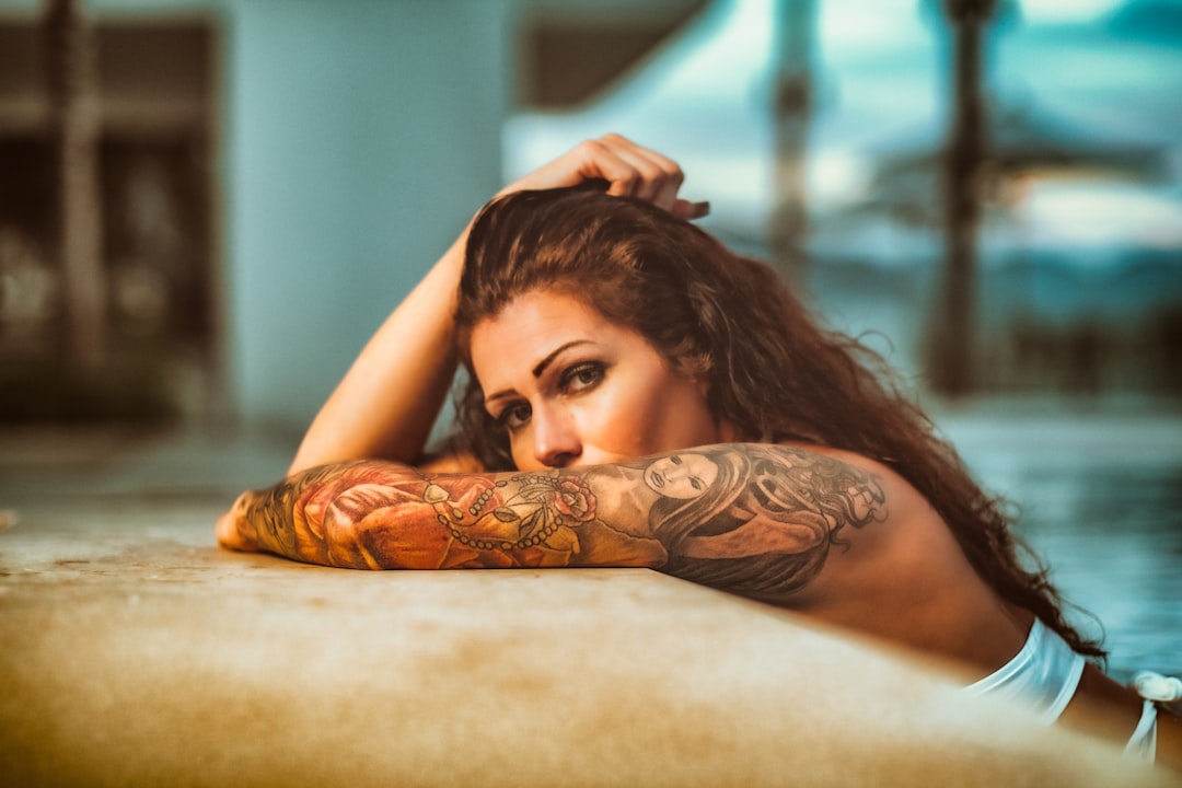 woman with black tattoo on her back lying on brown textile