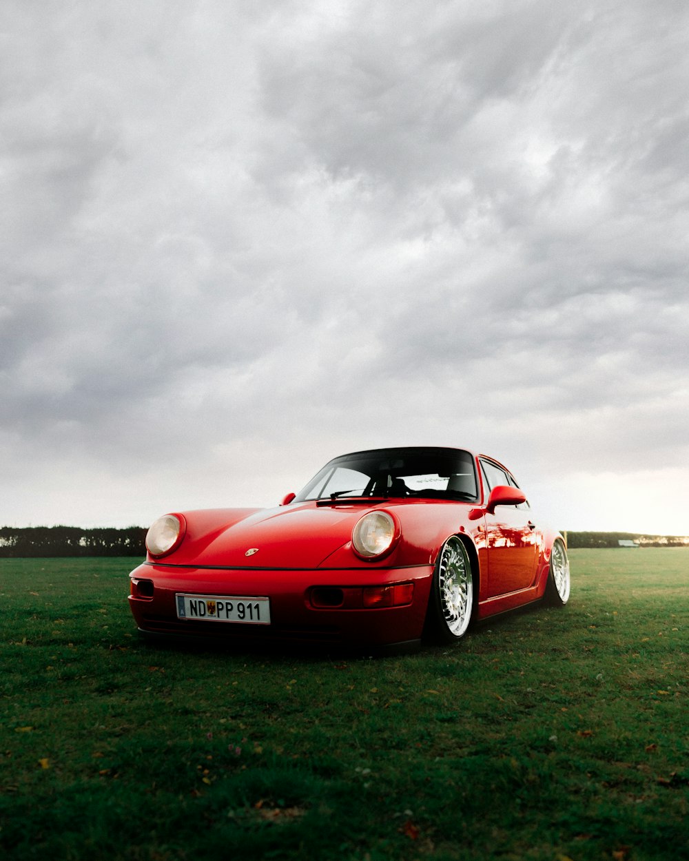 red ferrari 458 italia on green grass field under white clouds