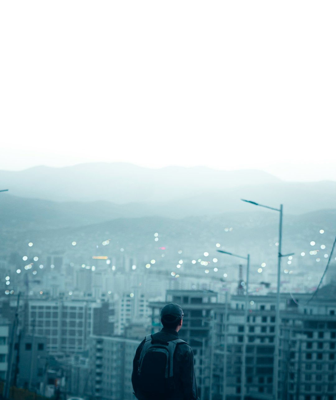 man in black jacket standing on top of building looking at city buildings during daytime