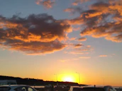 A warm amber-orange sunset casting a glow over a freshly detailed car parked by the ocean.