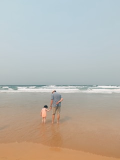 man and woman walking on beach during daytime