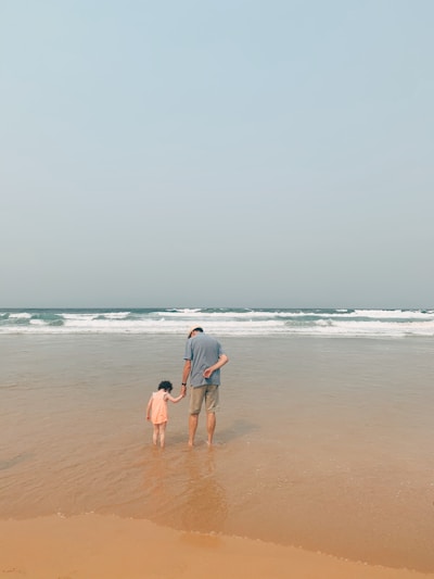 man and woman walking on beach during daytime