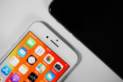 Two smartphones are shown, with one displaying a colorful home screen featuring various app icons such as Mail, Clock, and Calendar, with vibrant orange and yellow shades. The other phone, partially visible, appears to be black.