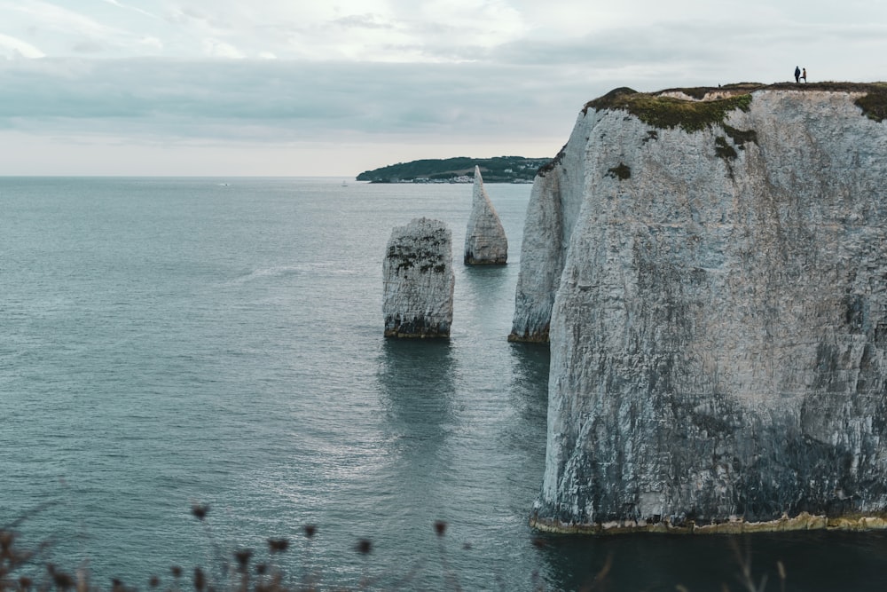 Formation rocheuse grise sur la mer sous les nuages blancs pendant la journée