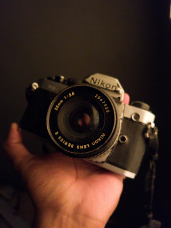 Close-up of hands gently holding a vintage camera, bathed in warm reddish light.